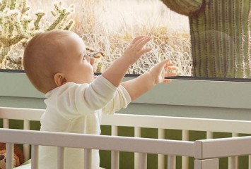 Schallschutz-Baby im Kinderbett vor Fenster